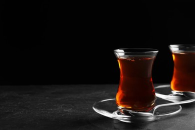 Photo of Glasses with traditional Turkish tea on black table, space for text