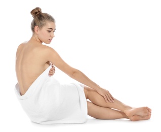 Young woman with soft towel sitting on white background