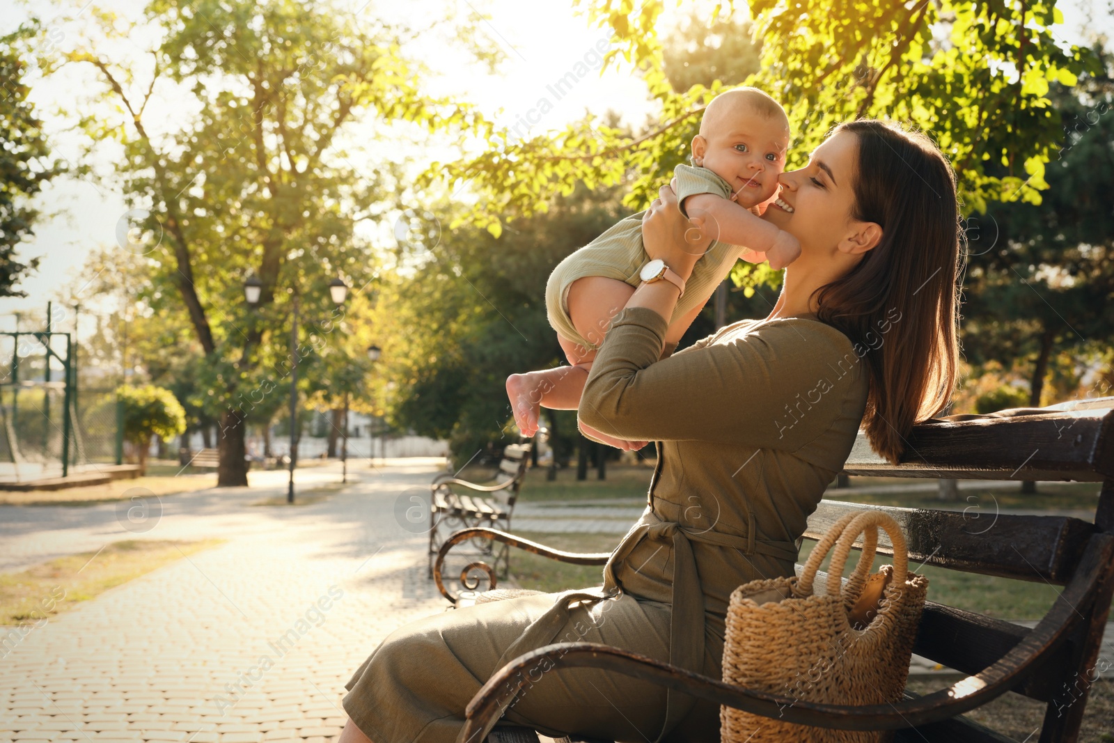 Photo of Young mother with her cute baby on bench in park