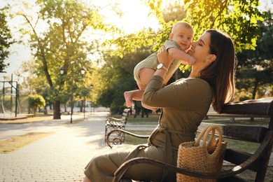 Photo of Young mother with her cute baby on bench in park