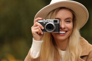 Autumn vibes. Smiling woman with camera taking photo outdoors, space for text