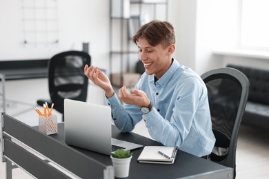 Photo of Man using video chat during webinar at table in office