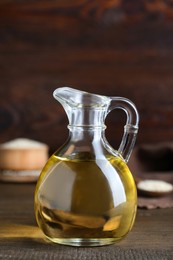 Photo of Jug of organic sesame oil and seeds on wooden table, closeup