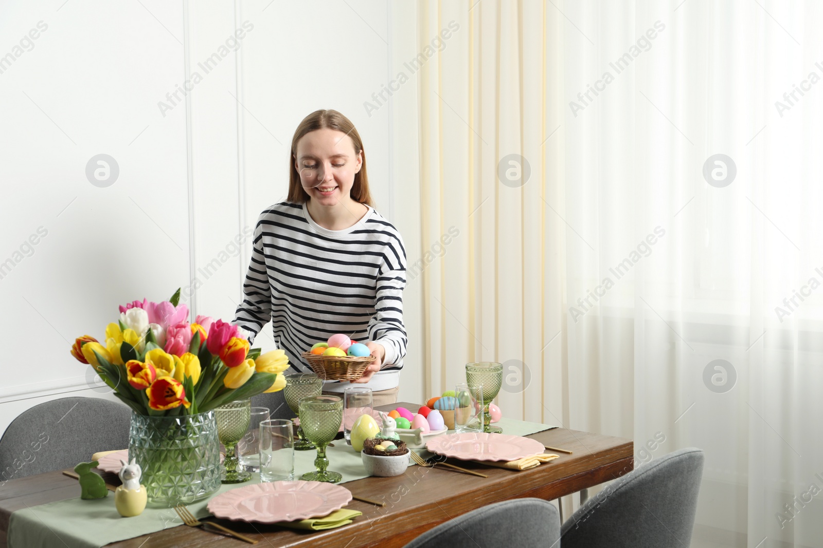 Photo of Woman setting table for festive Easter dinner at home