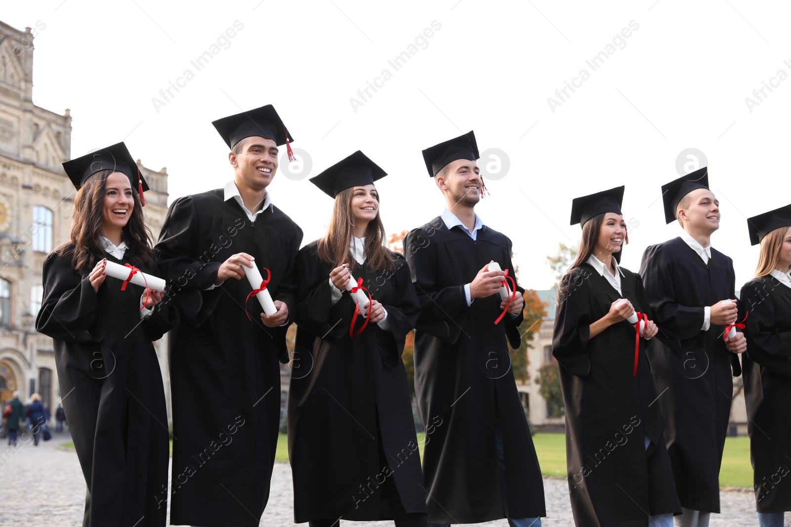 Photo of Happy students with diplomas outdoors. Graduation ceremony