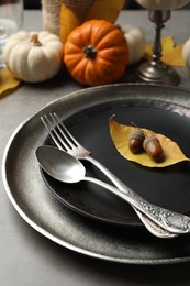 Seasonal table setting with pumpkins and other autumn decor on grey background, closeup