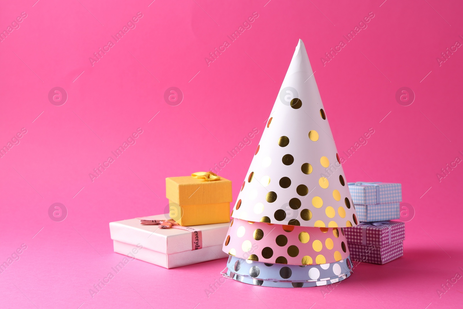 Photo of Party hats and gift boxes on pink background