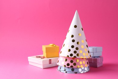 Photo of Party hats and gift boxes on pink background