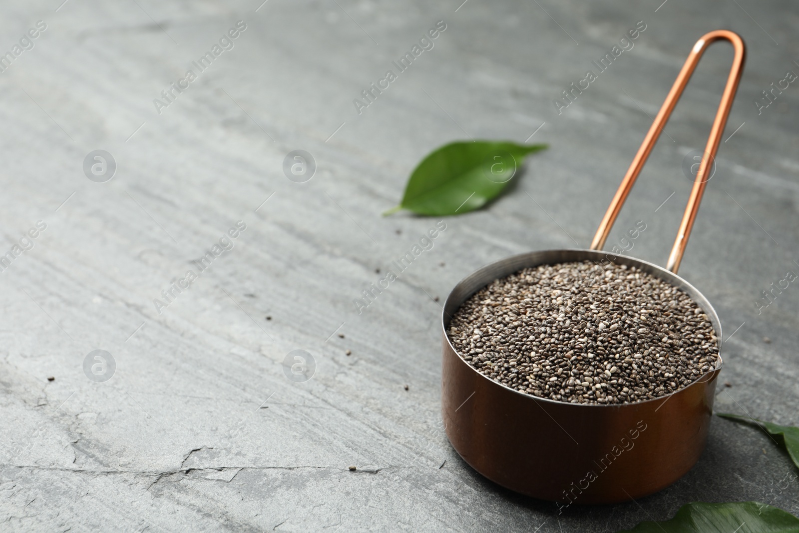 Photo of Saucepan with chia seeds on slate table. Space for text