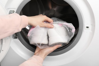 Photo of Woman putting stylish sneakers into washing machine, closeup