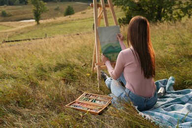 Photo of Young woman drawing landscape with soft pastels in nature. Space for text