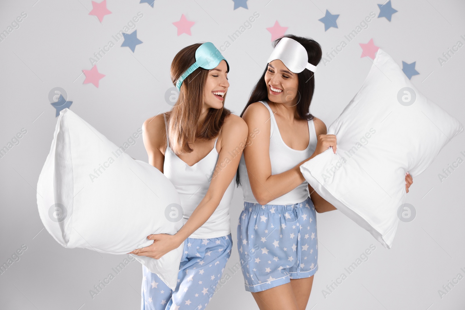 Photo of Beautiful women with pillows on light grey  background. Bedtime