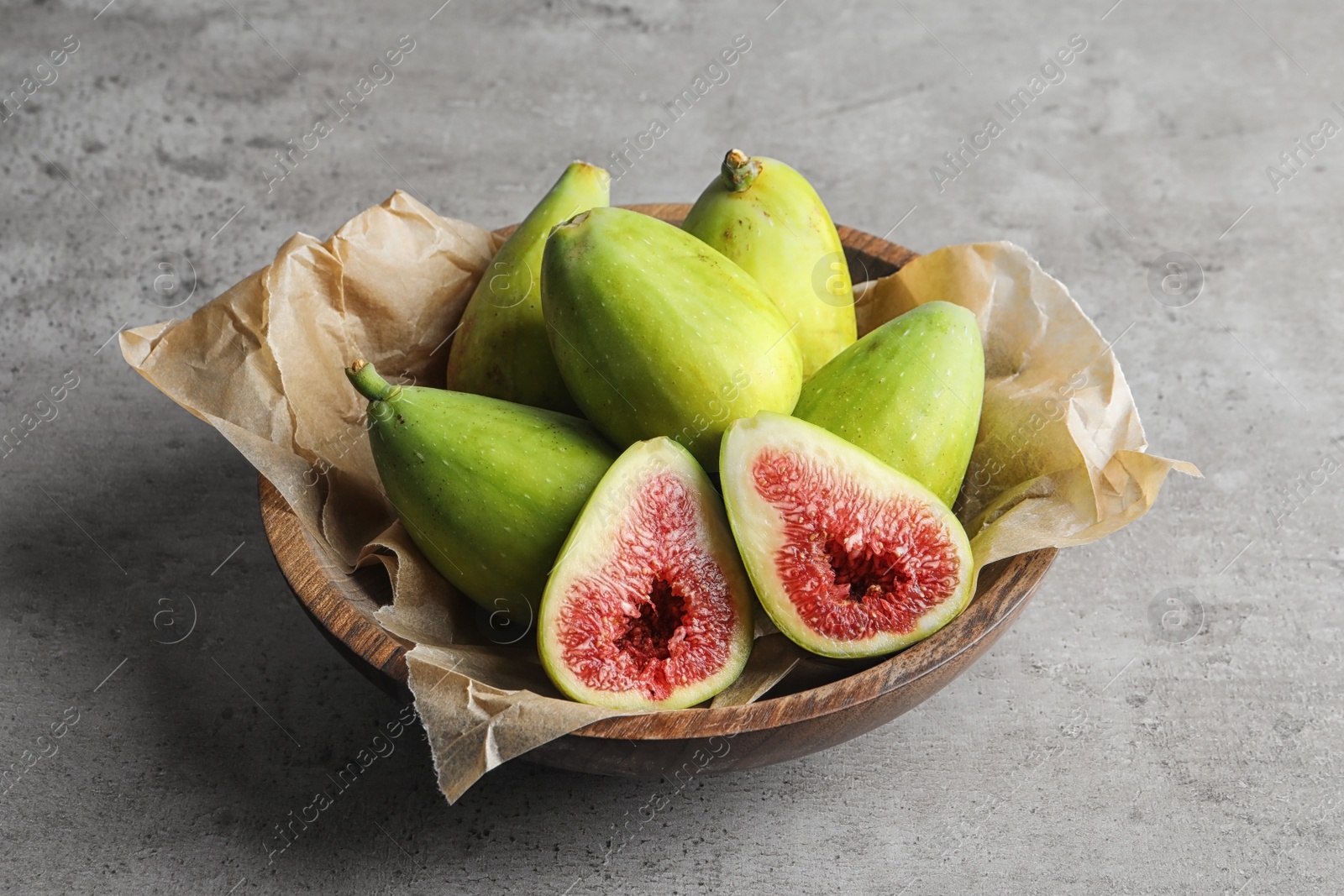 Photo of Bowl with fresh ripe figs on gray background. Tropical fruit