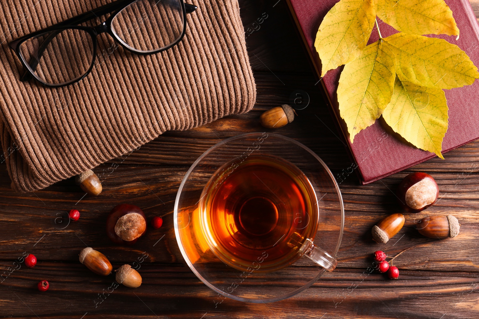 Photo of Flat lay composition with cup of aromatic tea and soft sweater on wooden table. Autumn atmosphere