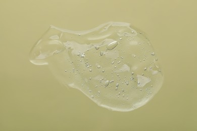 Photo of Sample of cleansing gel on pale olive background, top view. Cosmetic product