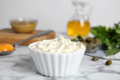 Tasty tartar sauce and ingredients on white marble table