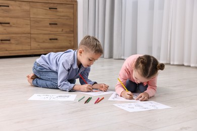 Photo of Cute little children coloring on warm floor at home. Heating system
