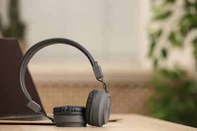 Modern headphones and laptop on table indoors, space for text