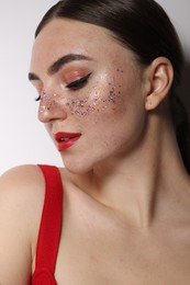 Photo of Beautiful woman with glitter freckles on light background, closeup
