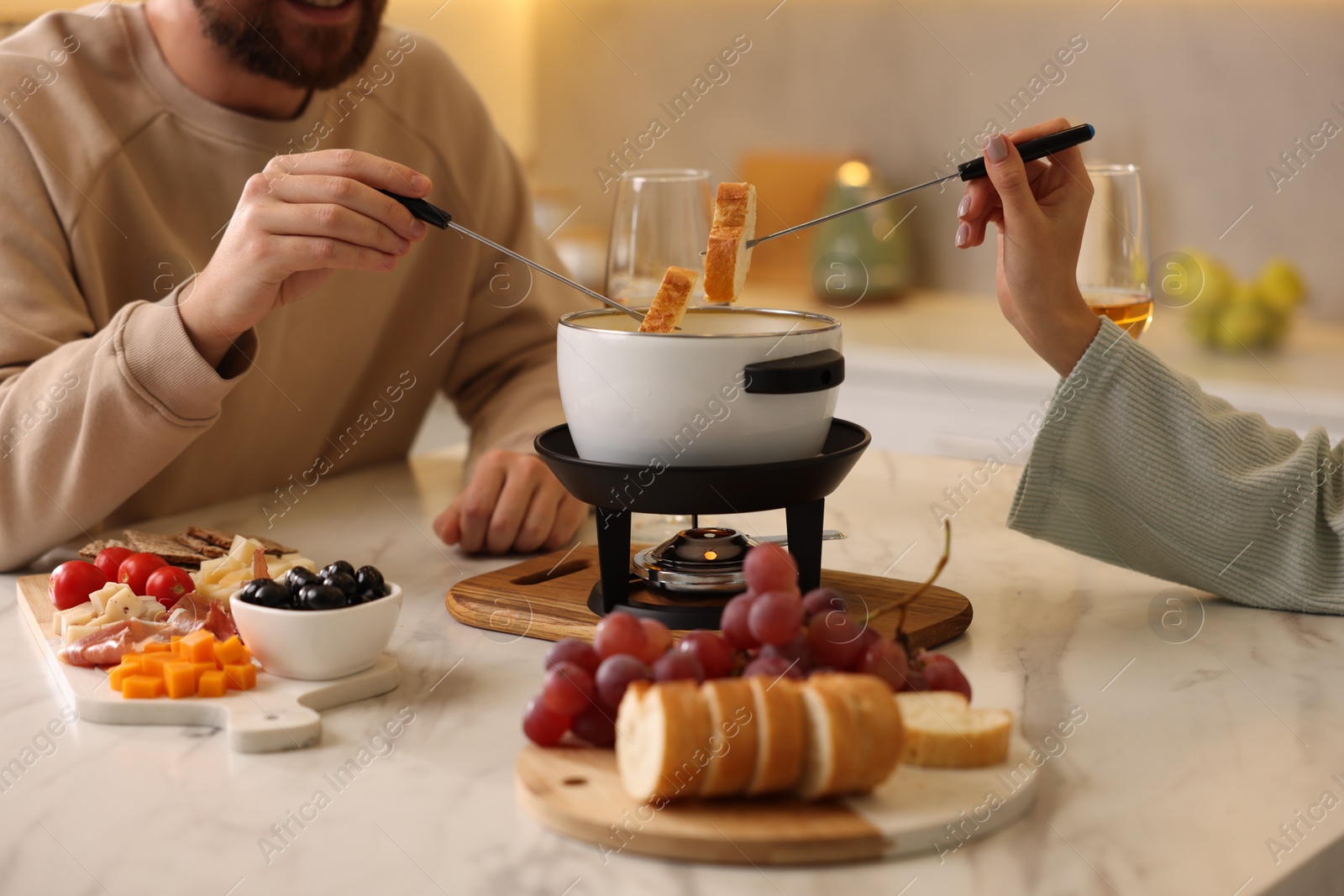 Photo of Couple enjoying fondue during romantic date in kitchen, closeup