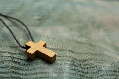 Photo of Christian cross on wooden table, closeup. Space for text