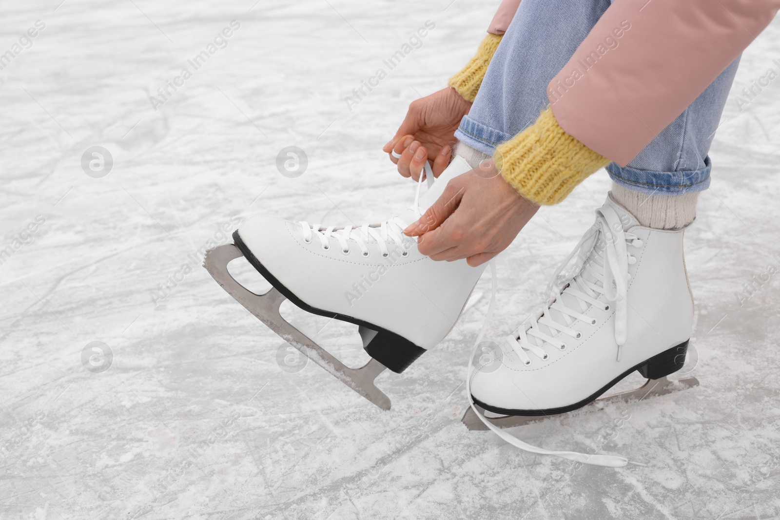 Photo of Woman lacing figure skates on ice, closeup