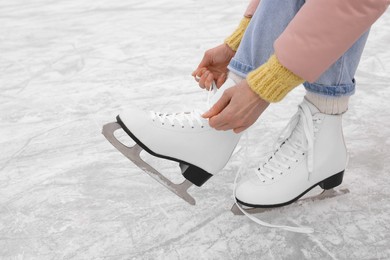 Photo of Woman lacing figure skates on ice, closeup