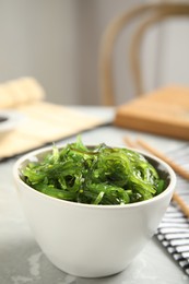 Photo of Japanese seaweed salad served on light marble table