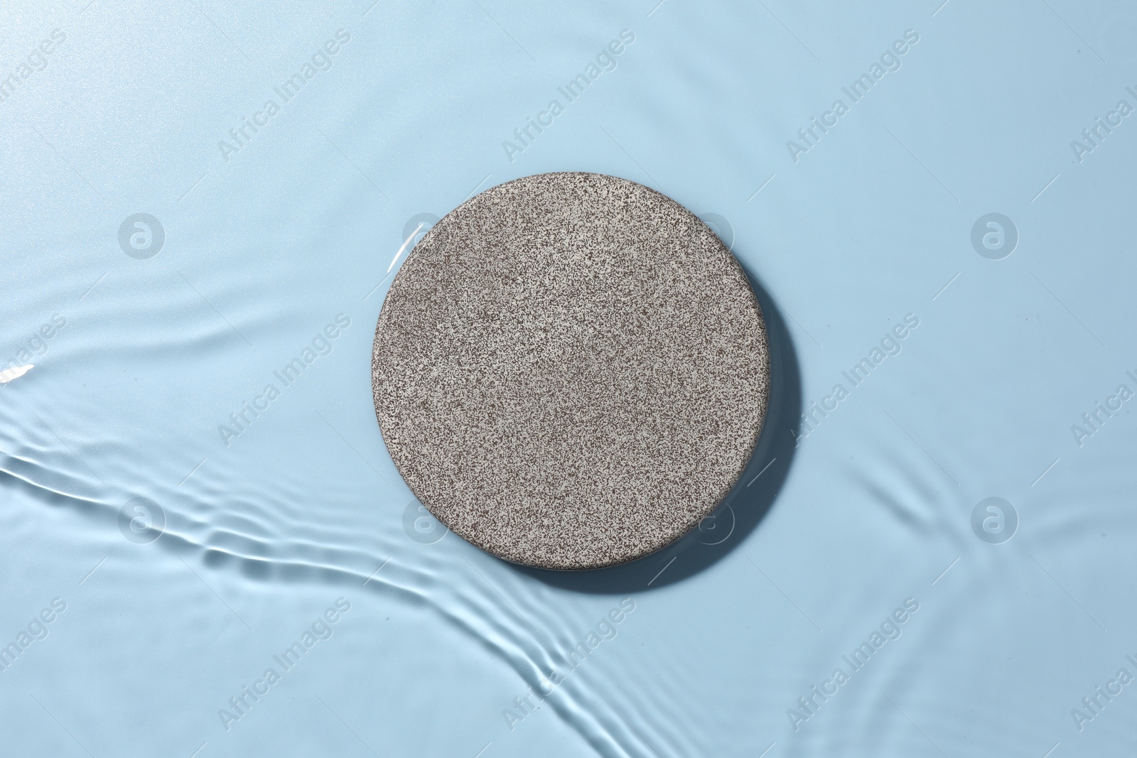 Photo of Presentation for product. Stone podium in water on light blue background, top view