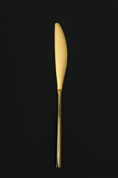 Photo of Shiny elegant gold knife on black background, top view