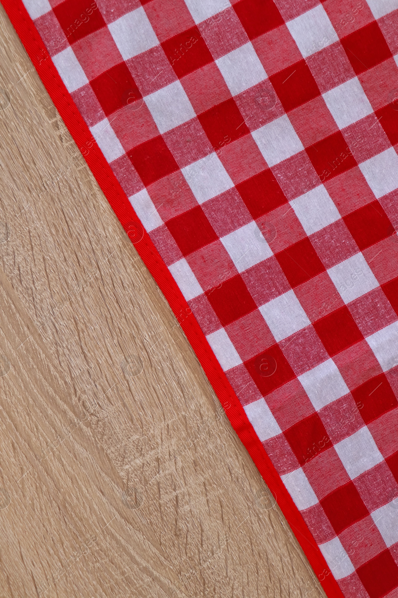 Photo of Checkered picnic cloth on wooden table, top view. Space for text