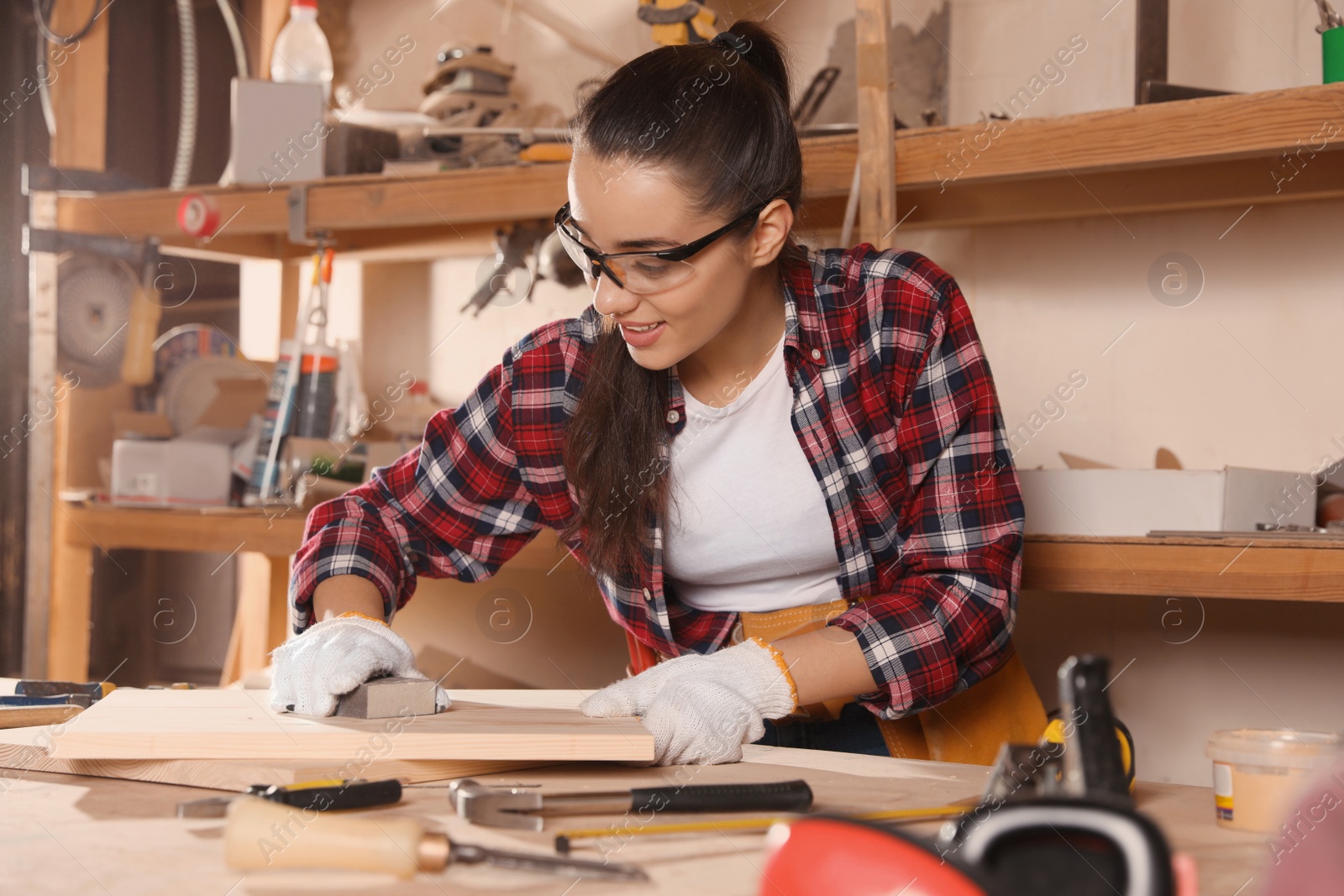 Photo of Female carpenter polishing wooden board in workshop