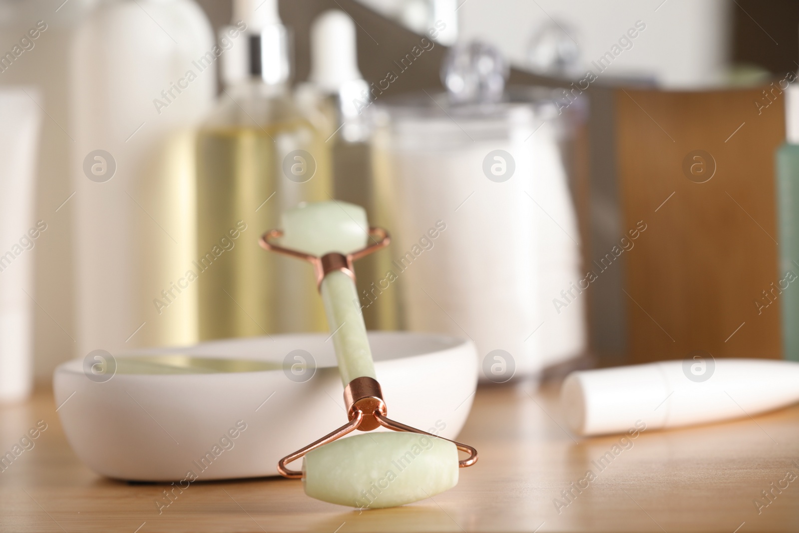 Photo of Natural face roller and cosmetic products on wooden table