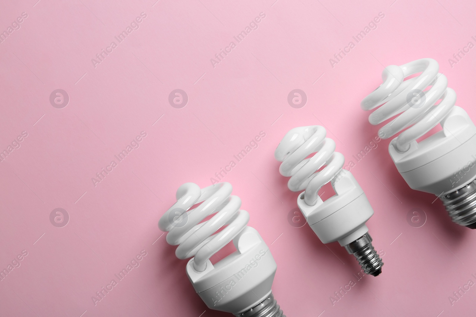 Photo of New fluorescent lamp bulbs on pink background, top view. Space for text