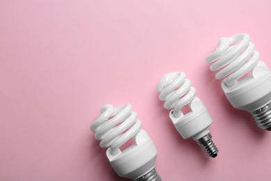 Photo of New fluorescent lamp bulbs on pink background, top view. Space for text