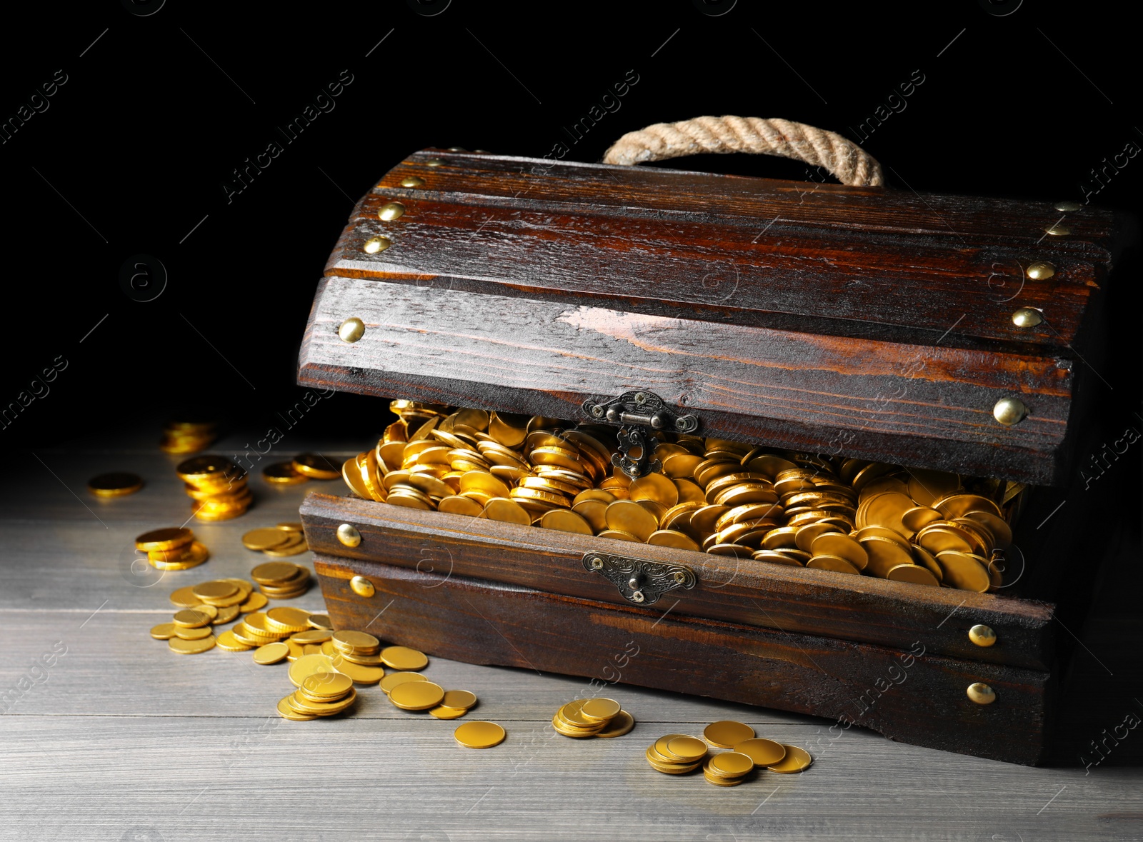 Image of Open treasure chest with gold coins on grey wooden table