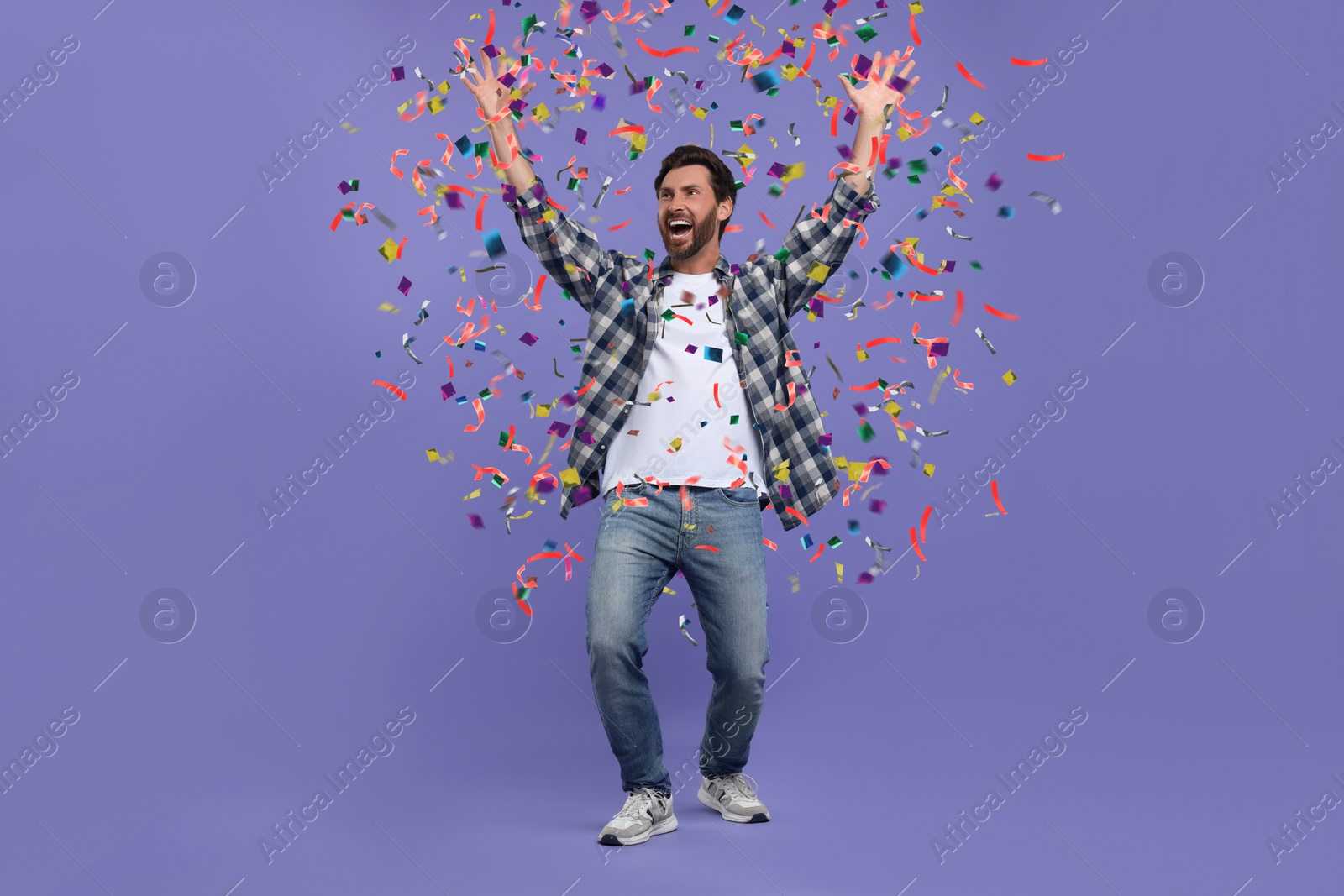 Image of Happy man under falling confetti on violet background