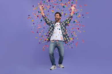 Happy man under falling confetti on violet background