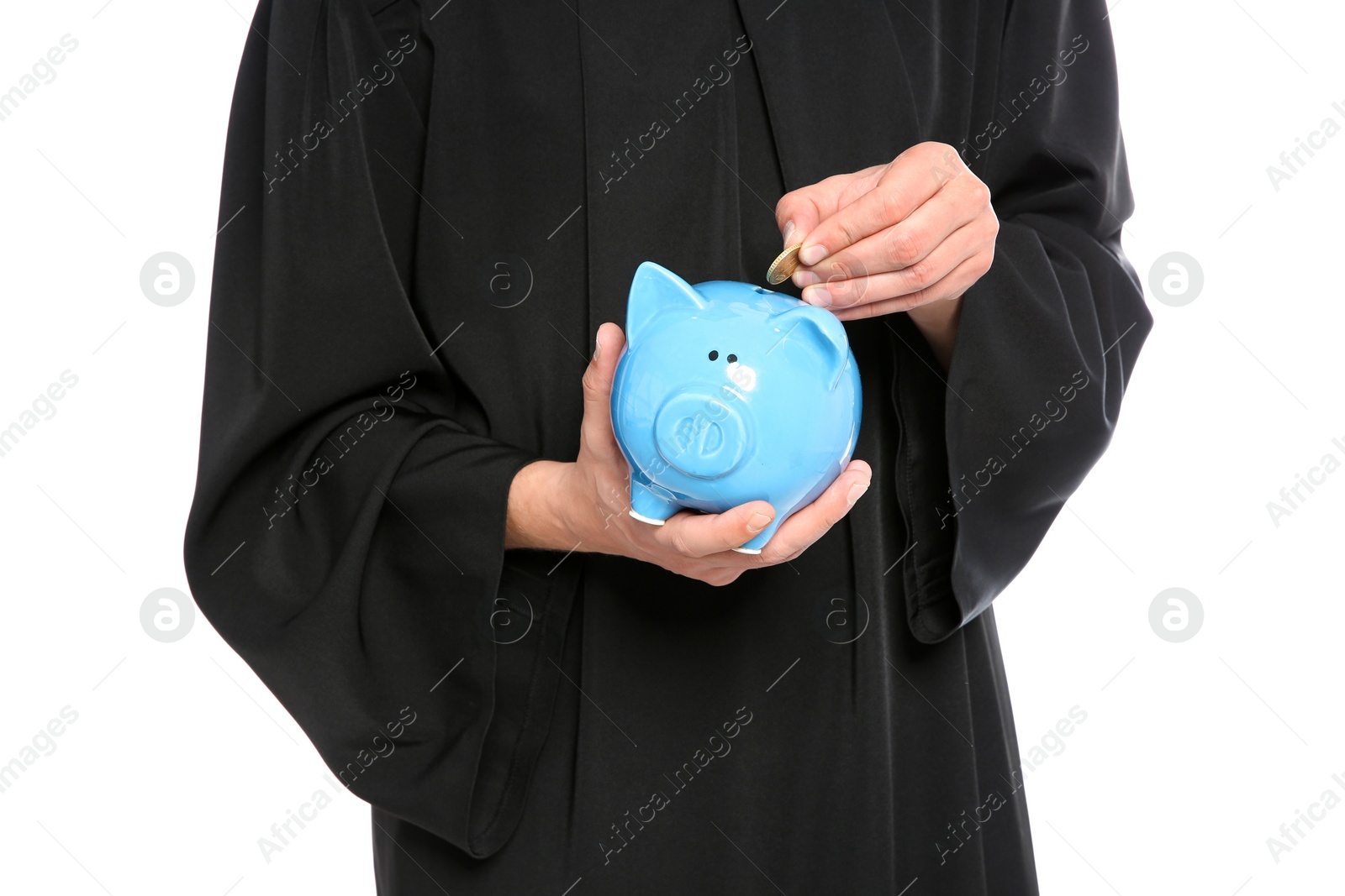 Photo of Young graduate putting coin into piggy bank on white background, closeup