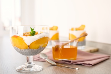 Tasty peach dessert with yogurt and chia seeds served on wooden table. Space for text