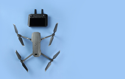 Photo of Modern drone with controller on blue background, flat lay. Space for text