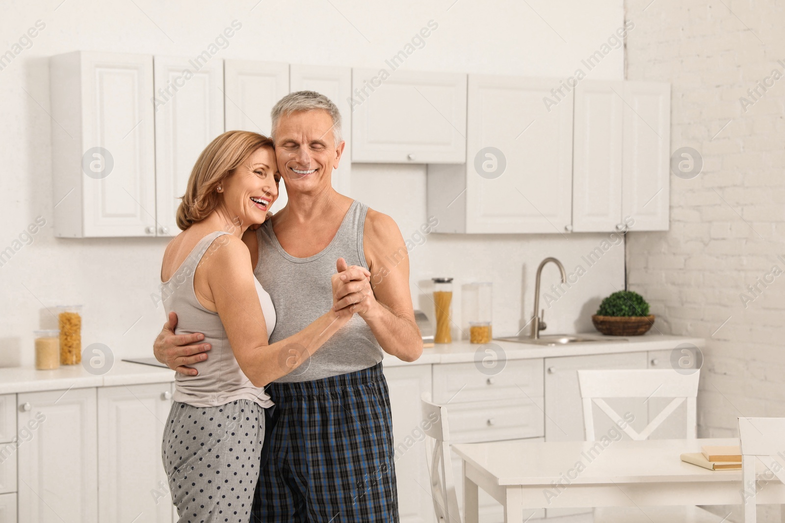 Photo of Happy senior couple dancing together in kitchen