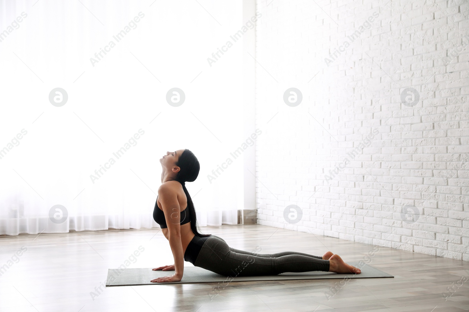 Photo of Young woman practicing cobra asana in yoga studio. Bhujangasana pose