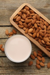 Photo of Glass of almond milk and almonds on wooden table, top view