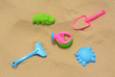 Photo of Set of colorful beach toys on sand, above view