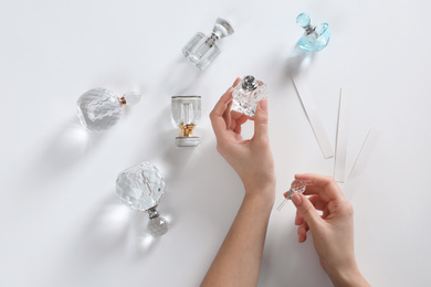 Photo of Woman applying perfume on white background, top view