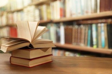 Image of Different books on wooden table in library, space for text