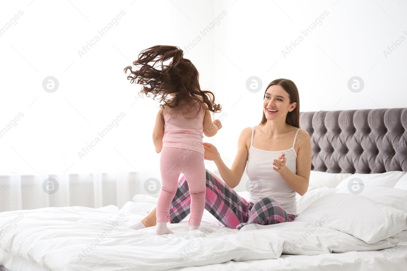 Photo of Happy mother with little daughter playing on bed