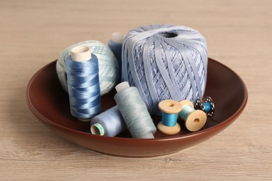 Color sewing threads in bowl on wooden table
