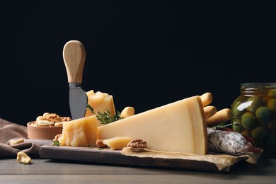 Photo of Delicious parmesan cheese with olives and walnuts on wooden table